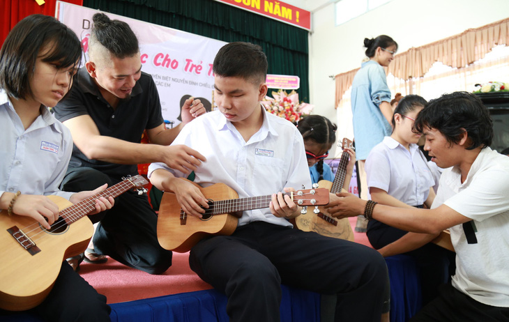 Anh Lương Hy (phải) và anh Bửu Thăng (thứ hai, từ trái sang) dạy các em khiếm thị làm quen với đàn