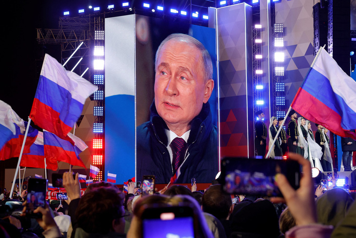 Tổng thống Nga Vladimir Putin xuất hiện trên màn hình sân khấu, khi ông Putin tham dự sự kiện đánh dấu kỷ niệm 10 năm sáp nhập Crimea tại Quảng trường Đỏ, trung tâm Matxcơva, Nga, ngày 18-3 - Ảnh: REUTERS