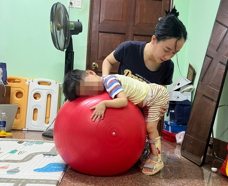 Chị Q. đang tập vật lý trị liệu cho con - Ảnh: Gia đình cung cấp