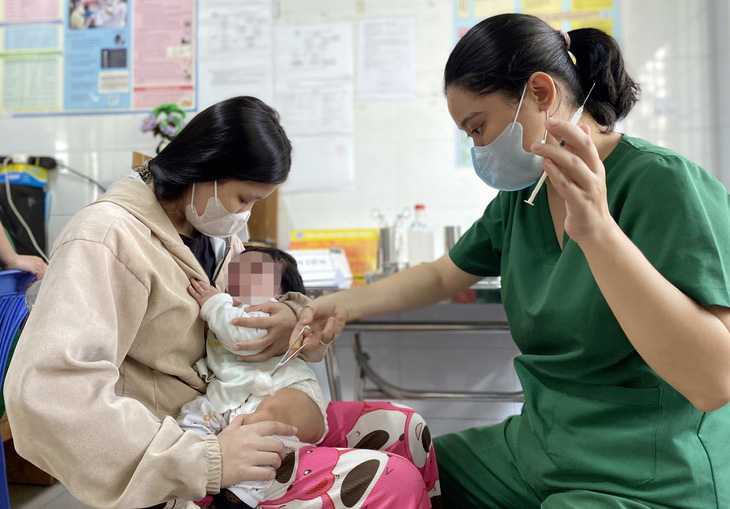 Phụ huynh đưa trẻ đi tiêm vắc xin trong chương trình tiêm chủng mở rộng tại TP.HCM - Ảnh: XUÂN MAI