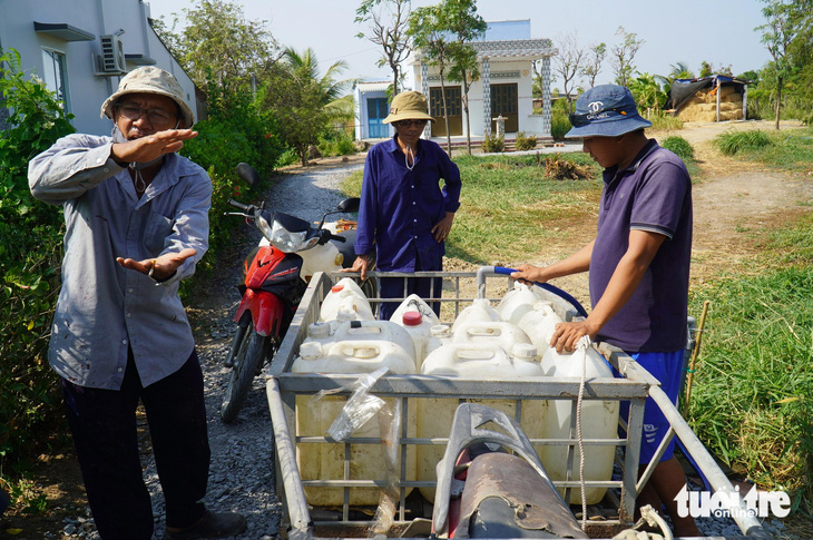 Người dân tại huyện Tân Phú Đông tập trung tại một vòi nước công cộng miễn phí hứng về sử dụng - Ảnh: MẬU TRƯỜNG