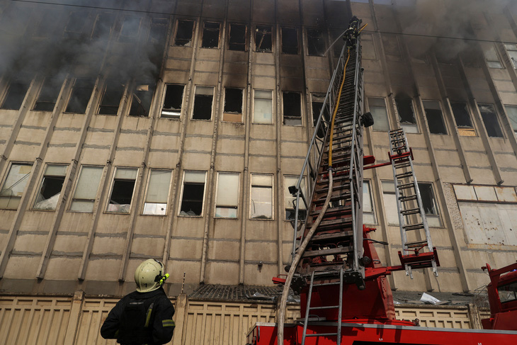 Lính cứu hỏa nỗ lực chữa cháy tại một nhà in bị tấn công bằng tên lửa của Nga ở Kharkov, Ukraine ngày 20-3 - Ảnh: REUTERS