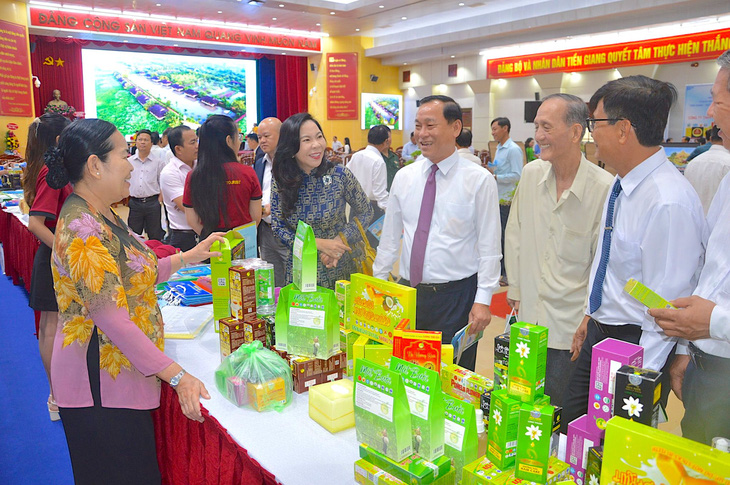Chủ tịch UBND tỉnh Tiền Giang Nguyễn Văn Vĩnh (đứng giữa thắt cà vạt tím) tại một gian hàng trưng bày sản phẩm tiêu biểu của tỉnh - Ảnh: MẬU TRƯỜNG