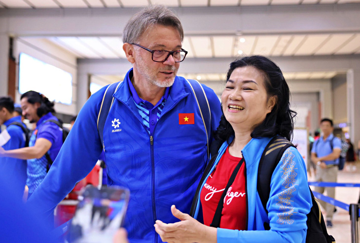 HLV Troussier chụp ảnh cùng cổ động viên Việt Nam ở sân bay - Ảnh: VIỆT PHONG