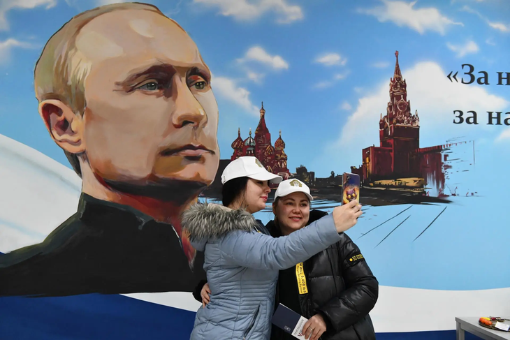 Cử tri Nga chụp hình với áp-phích ông Putin sau khi bỏ phiếu. Ảnh: efe.com