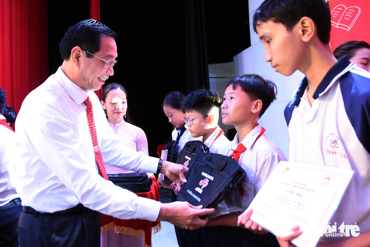 Phó chủ tịch UBND tỉnh Đồng Nai Võ Văn Phi trao học bổng, cặp sách cho các em học sinh - Ảnh: A LỘC