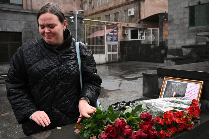 Một người phụ nữ rơi nước mắt khi đặt hoa tại khu vực tưởng niệm tạm thời trước Đại sứ quán Nga ở Yerevan của Armenia, ngày 23-3, một ngày sau vụ xả súng ở Nga - Ảnh: AFP