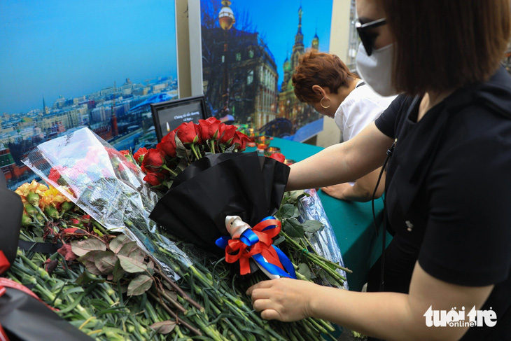 Một người dân mang theo bó hoa với ruy băng màu quốc kỳ Nga đến đặt trước cửa Đại sứ quán Nga tại Hà Nội - Ảnh: DANH KHANG