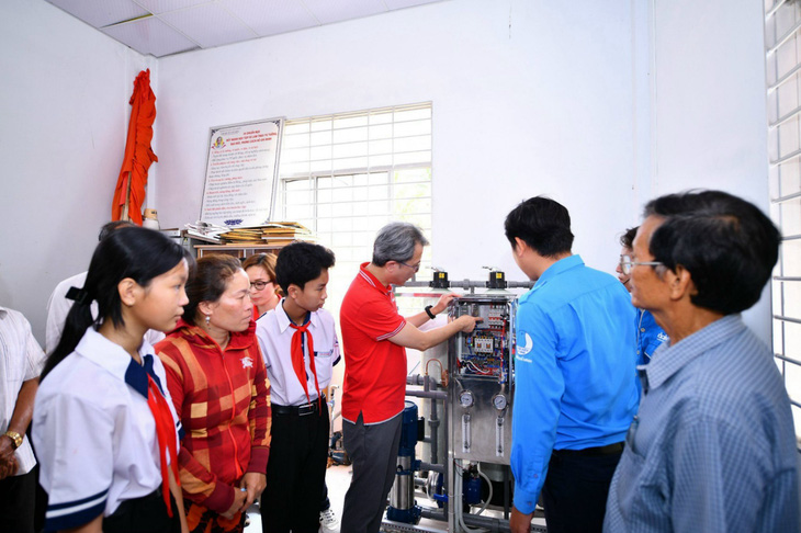 Người dân, học sinh và đại diện chính quyền địa phương tìm hiểu về cách sử dụng máy lọc nước