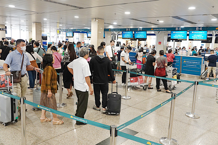 Khách xếp hàng đợi soi hành lý tại sân bay Tân Sơn Nhất vào chiều 20-3 - Ảnh: T.T.D.