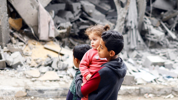 Những đứa trẻ Palestine đứng nhìn một ngôi nhà đổ nát sau loạt không kích của Israel tại Rafah, phía nam Dải Gaza, ngày 24-3 - Ảnh: Reuters