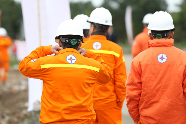 Công nhân ngành điện mặc đầy đủ áo bảo hộ sáng màu và đội mũ bảo vệ trước khi ra công trường - Ảnh: HÀ QUÂN