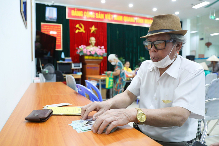 Người dân kiểm tra lại lương hưu sau khi lĩnh từ cán bộ bưu điện tại một điểm chi trả ở Hà Nội - Ảnh: DANH KHANG