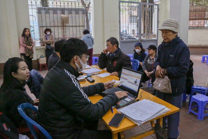 Nhân viên bưu điện kiểm tra thông tin của người hưởng lương hưu qua thẻ từ - Ảnh: HÀ QUÂN