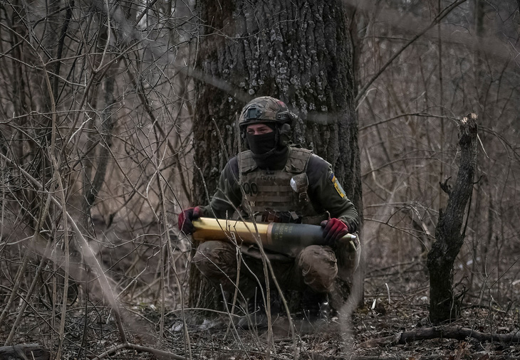 Binh sĩ Ukraine ôm một quả đạn pháo chuẩn bị được bắn vào các vị trí quân Nga hôm 5-3 - Ảnh: REUTERS