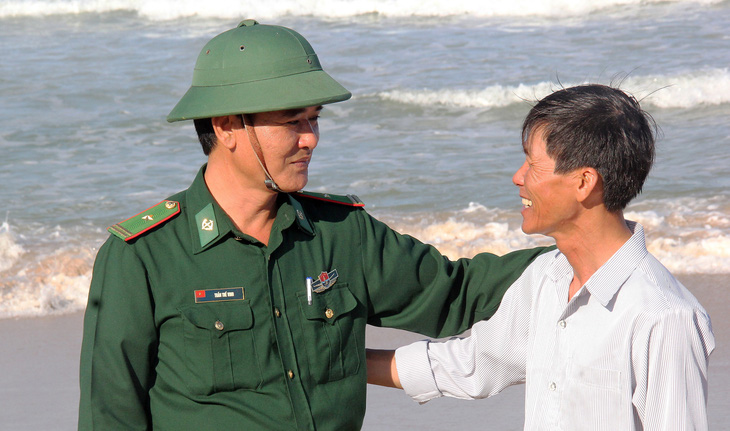 Thiếu tá Trần Thế Vinh, chính trị viên Đồn biên phòng Bình Hải, trò chuyện với ông Võ Văn - người phát hiện gói ma túy - Ảnh: TRẦN MAI