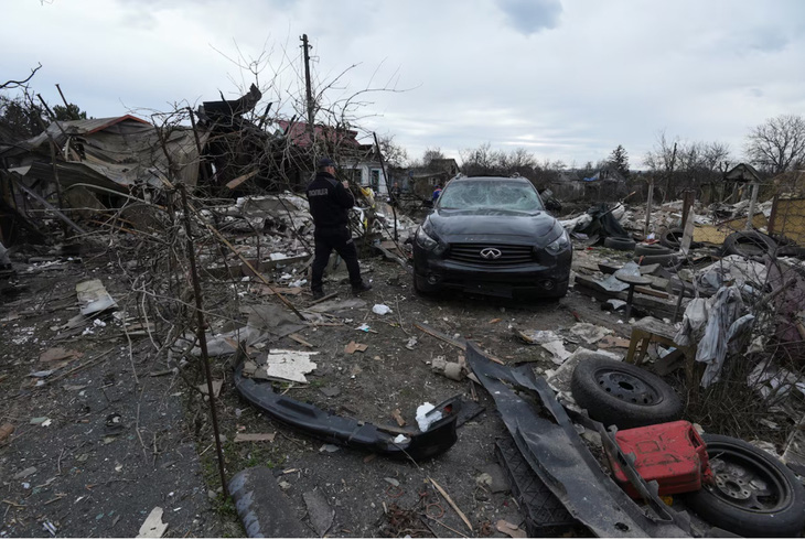 Một cảnh sát đang kiểm tra khu dân cư bị hư hại nặng nề sau cuộc tấn công bằng tên lửa và máy bay không người lái của Nga - Ảnh: REUTERS