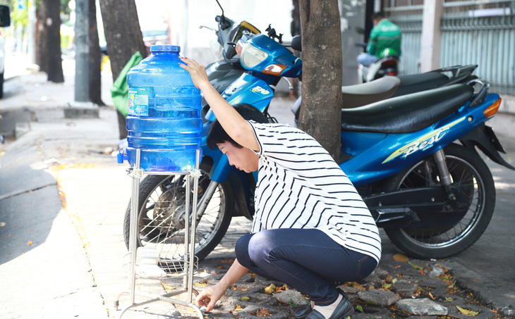 Bà Mai Thanh đặt bình nước miễn phí phục vụ bà con - Ảnh: AN VI