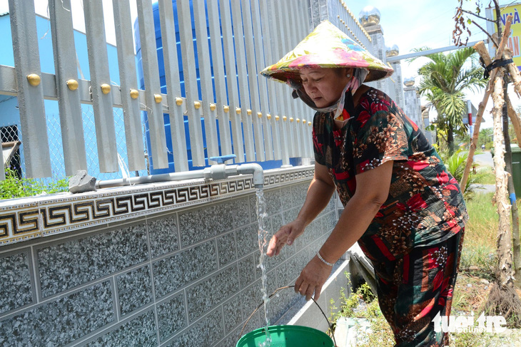 Người dân các huyện phía đông tỉnh Tiền Giang dùng xô nhựa hứng nước miễn phí tại các vòi công cộng dọc đường - Ảnh: HOÀI THƯƠNG