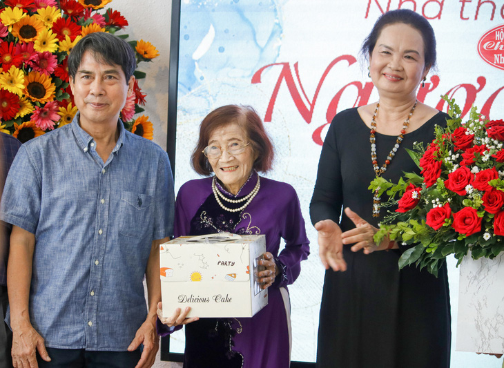 Nhà thơ Phạm Như Vân (giữa) nhận bánh kem đón sinh nhật tuổi 85 từ kiến trúc sư Nguyễn Trường Lưu (bìa trái) và chủ tịch Hội Nhà văn TP.HCM Trịch Bích Ngân (bìa phải) - Ảnh: HỒ LAM