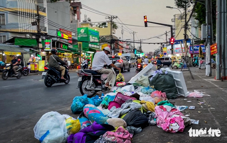 Một người đàn ông chạy xe máy đến vứt rác xuống đường Phan Văn Trị (gần đường Nguyên Hồng, phường 11, quận Bình Thạnh) - Ảnh: CHÂU TUẤN