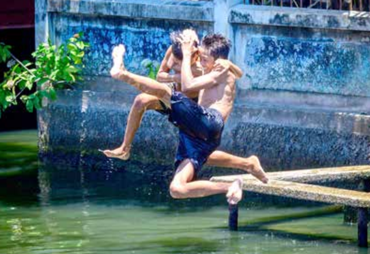 Hai đứa trẻ nhảy xuống một con kênh để giải nhiệt ở thủ đô Bangkok (Thái Lan) - Ảnh: AFP