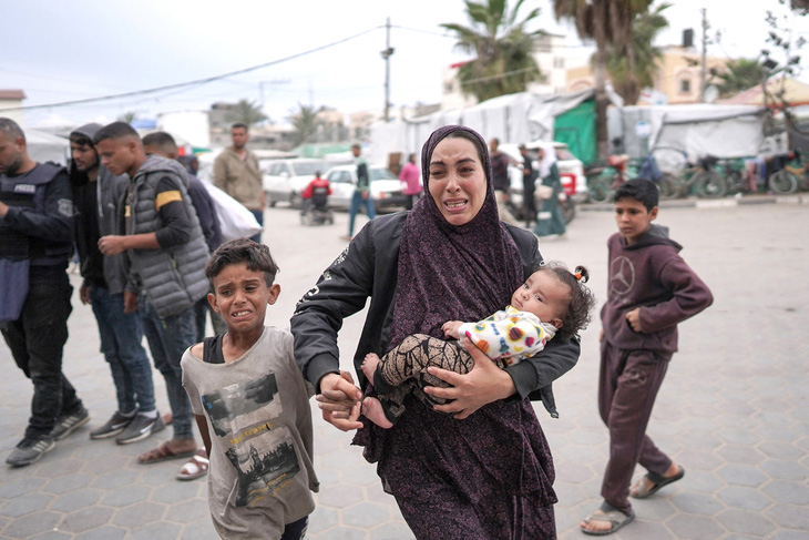 Một gia đình Palestine chạy đến bệnh viện sau một cuộc không kích ở miền trung Dải Gaza ngày 8-4 - Ảnh: AFP
