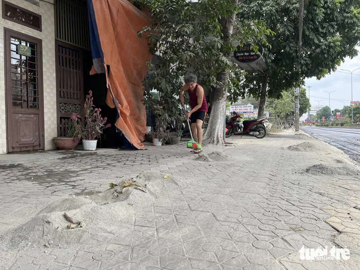 Chỉ sau một đêm, cuộc sống của người dân trên đường Nguyễn Trãi bị đảo lộn, họ phải quét lại lượng đất, bụi bám từ nhà ra tận vỉa hè - Ảnh: TRẦN MAI