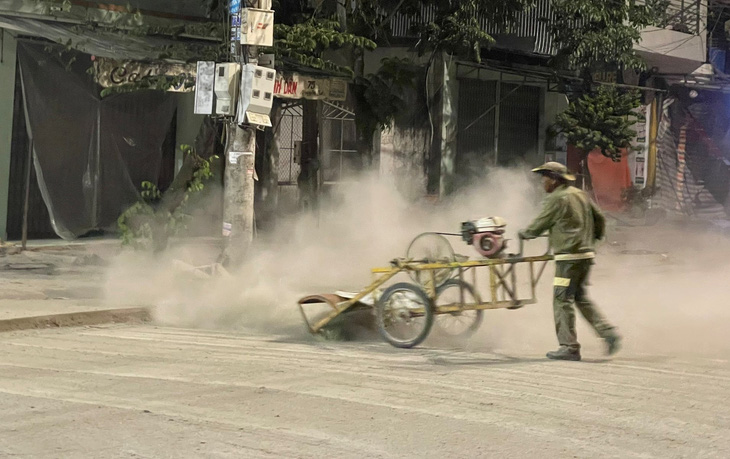 Bụi mù mịt với cách thi công làm sạch mặt đường bằng cách sử dụng máy nén khí thổi - Ảnh: TRẦN MAI