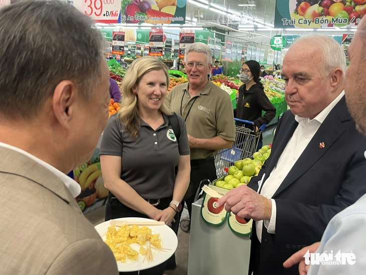 Bộ trưởng Nông nghiệp tiểu bang Washington ông Derek Sandison thử nông sản Việt Nam tại chuyến thăm và làm việc ở siêu thị MM An Phú - Ảnh: N.BÌNH