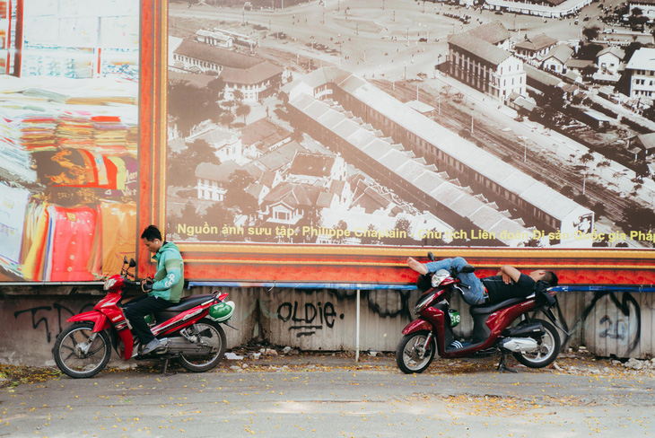 Những chiếc bảng hiệu ngay trước bức tường của Tổng lãnh sự quán Pháp tại đường Lê Duẩn trở thành "chiếc ô" lớn che nắng tạm thời cho các bác tài - Ảnh: THANH HIỆP