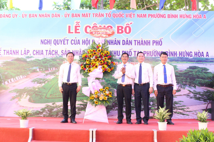 Bí thư quận Bình Tân (bìa trái) trao hoa chúc mừng lãnh đạo phường Bình Hưng Hòa A - Ảnh: L.T.