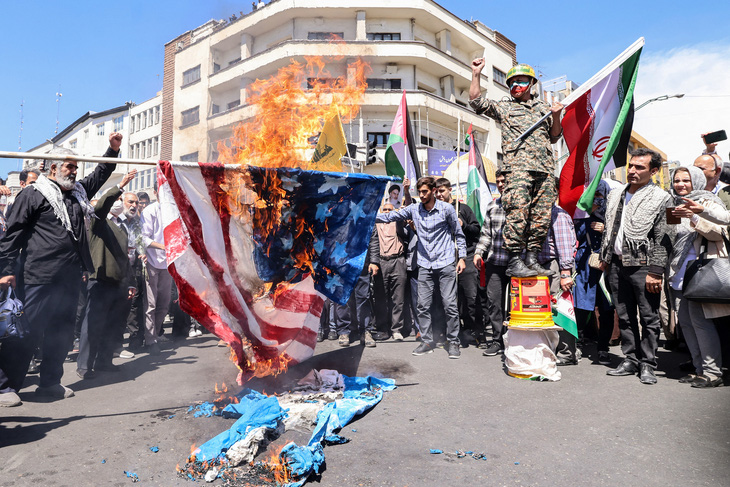 Người biểu tình ở Iran đốt cờ Mỹ và Israel sau vụ không kích vào Đại sứ quán Iran ở Syria - Ảnh: AFP