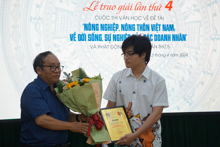Con trai nhà văn Lê Hoài Lương nhận giải nhất thay cho bố từ nhà thơ Trần Đăng Khoa - phó chủ tịch Hội Nhà văn Việt Nam - Ảnh: T.ĐIỂU