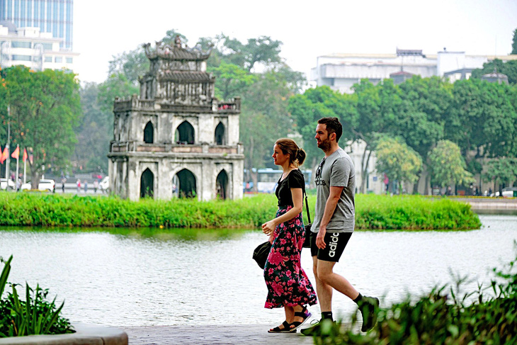 Hai du khách nước ngoài đi bộ bên bờ hồ Hoàn Kiếm ở thủ đô Hà Nội - Ảnh: NAM TRẦN