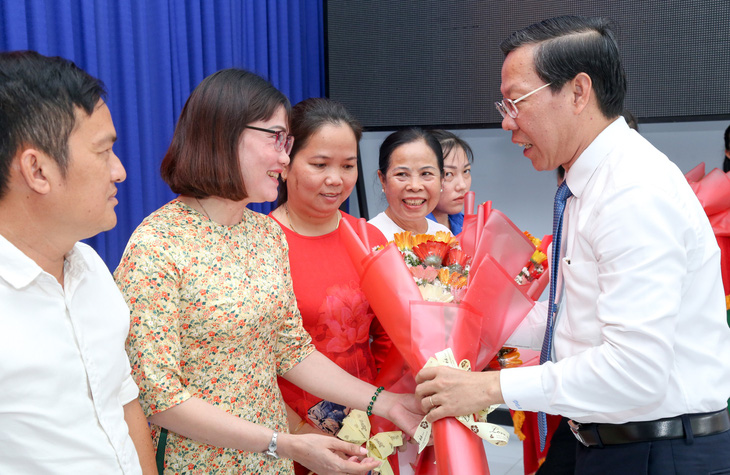 Chủ tịch UBND TP.HCM Phan Văn Mãi tặng hoa chúc mừng các cán bộ không chuyên trách được cử giữ chức vụ ở ấp mới - Ảnh: THẢO LÊ 