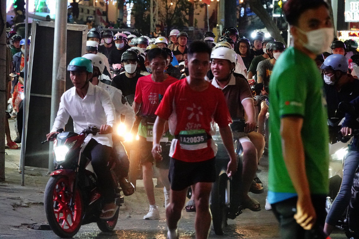 Vận động viên len lỏi chạy giữa dòng xe cộ tại Giải chạy bộ đêm âm nhạc ở Cần Thơ - Ảnh: B.K.