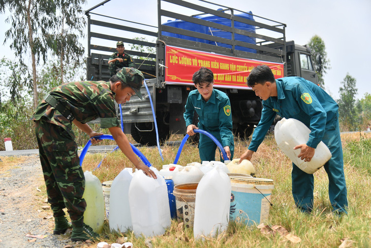 Lực lượng vũ trang tỉnh Kiên Giang bơm nước vào can nhựa cho người dân xã Phú Mỹ, huyện Giang Thành - Ảnh: PHƯƠNG VŨ