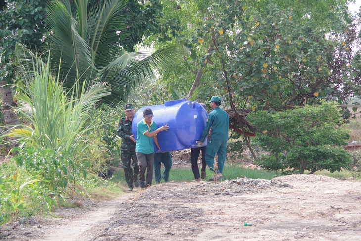 Nhiều nơi xa, lực lượng vũ trang tỉnh Kiên Giang còn giúp dân đưa các thùng chứa nước cho bà con - Ảnh: PHƯƠNG VŨ