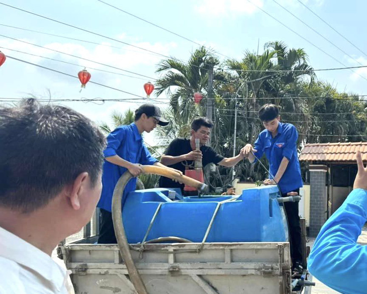 Lực lượng thanh niên địa phương hỗ trợ chuyển nước từ xe bồn xuống cho người dân - Ảnh: THẢO CHI