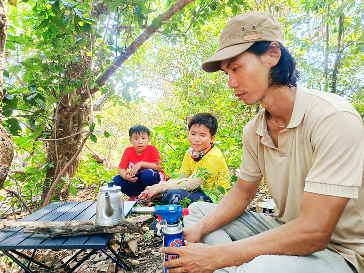 Nấu nước bằng dụng cụ khò lửa lúc đoàn nghỉ chân trong rừng - Ảnh: TRẦN HOÀI