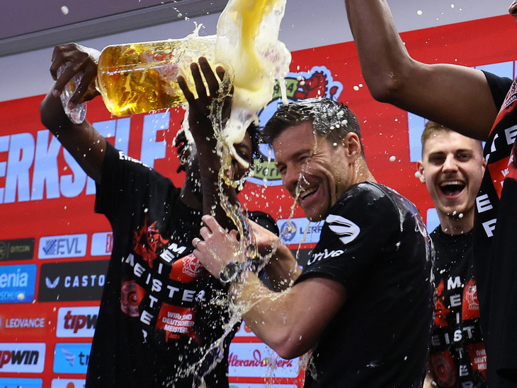 HLv Xabi Alonso tắm bia sau khi vô địch Bundesliga cùng Bayer Leverkusen - Ảnh: REUTERS