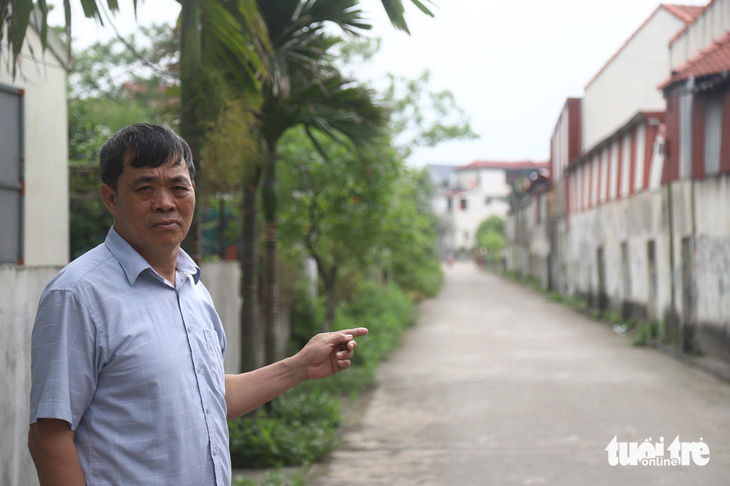 Ông Lê Văn Thụy chỉ về con đường làng được đổ bê tông từ nguồn tiền giao thầu đất nông nghiệp - Ảnh: DANH TRỌNG