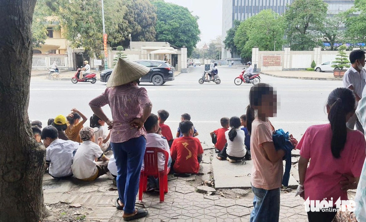 Phụ huynh đưa con đến đứng trước cổng trụ sở UBND tỉnh Nghệ An để phản đối việc sáp nhập điểm trường ở xã Ngọc Sơn, huyện Thanh Chương - Ảnh: DOÃN HÒA