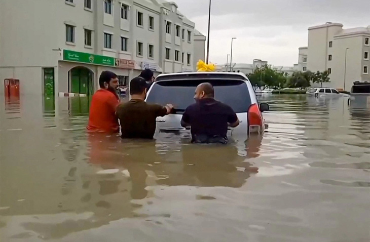 Người dân tại Dubai đẩy xe trong nước lụt ngày 16-4 - Ảnh: AFP/ ATIF BHATTI / ESN