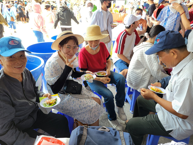 Được ban tổ chức phát bánh xèo miễn phí, nhiều người dân tham quan lễ hội bánh dân gian rất vui và khen bánh ăn ngon - Ảnh: CHÍ QUỐC 