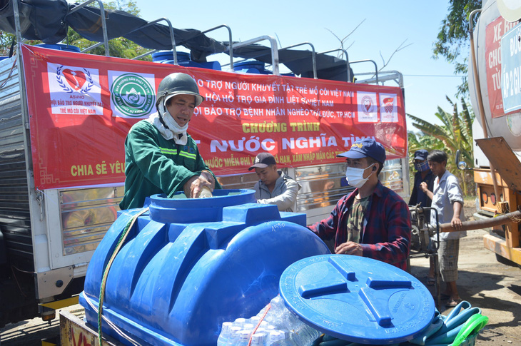 Người dân dùng xe chở theo bồn trữ nước đến các xe cấp nước miễn phí của nhà hảo tâm lấy nước về sử dụng - Ảnh: MẬU TRƯỜNG