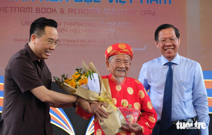 Chủ tịch UBND TP Phan Văn Mãi (bìa phải) và Cục trưởng Cục Xuất bản, In và Phát hành Nguyễn Nguyên (trái) chúc mừng cụ Nguyễn Đình Tư là Đại sứ văn hóa đọc trọn đời - Ảnh: LINH ĐOAN