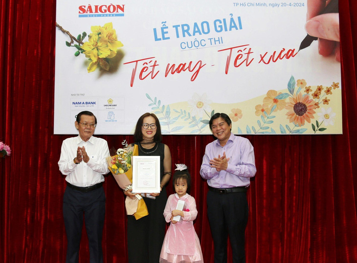 Chủ tịch Hội Nhà báo TP.HCM Nguyễn Tấn Phong (bìa trái) và Tổng biên tập báo Sài Gòn Giải Phóng Tăng Hữu Phong (bìa phải) trao giải nhất cho tác giả Thanh Loan - Ảnh: BTC