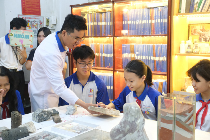 Các em học sinh Trường THCS Huỳnh Khương Ninh (quận 1, TP.HCM) thích thú sờ vào các mẫu hóa thạch trăm triệu năm tuổi - Ảnh: NGỌC PHƯỢNG